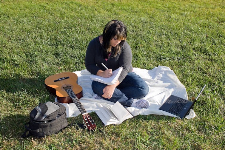 A teenage girl with a guitar, writing songs.