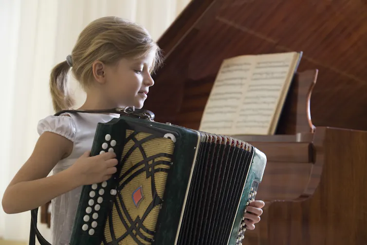 A young girl plays an accordion.