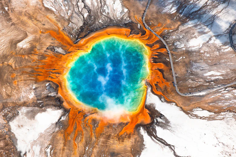 Aerial view of steaming, turquoise-coloured hot spring with orange ring.