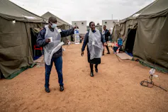 A row of military tents as a makeshift hospital with health professionals walking between them