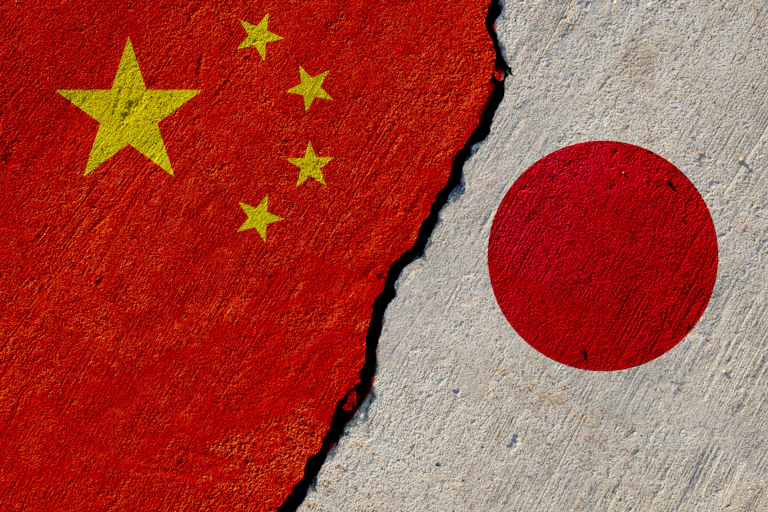 The Chinese and Japanese flags painted on a cracked concrete wall.