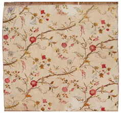 An intricately embroidered 18th-century bedcover of red flowers on a beige background.