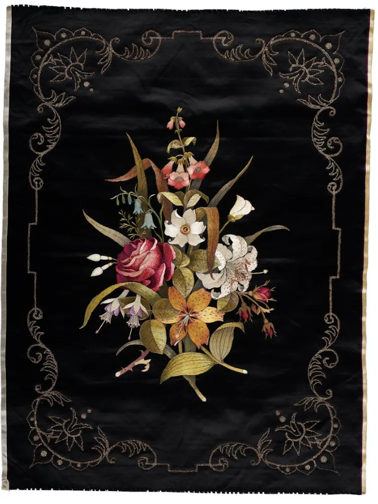 A black decorative panel embroidered with vivid flowers.