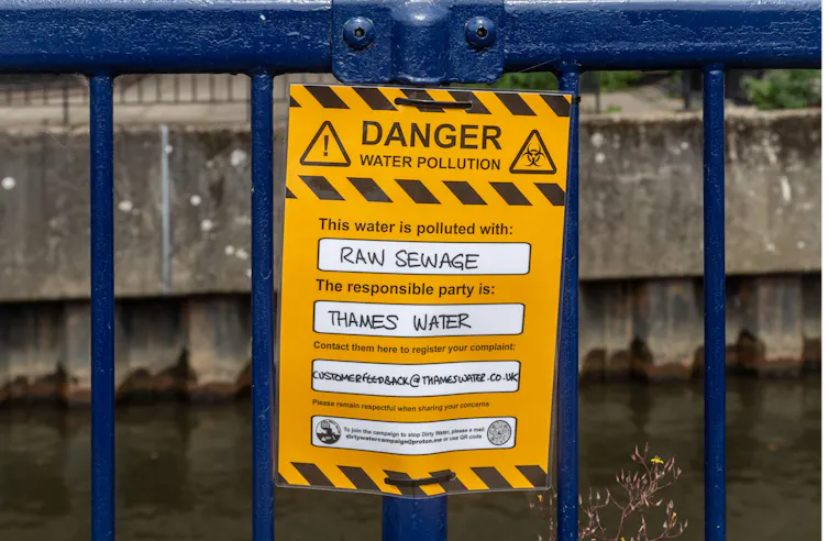 Protest sign reading Danger water pollution, this water is polluted with raw sewage.