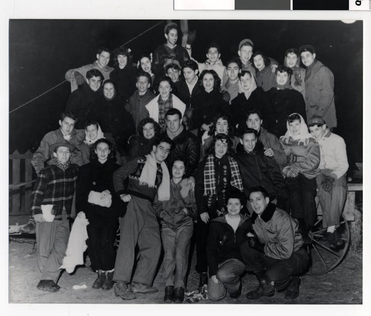 Black and white photograph of several rows of young people in heavy coats.