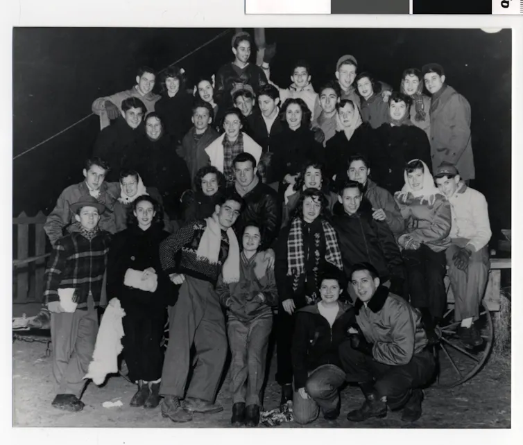 Black and white photograph of several rows of young people in heavy coats.