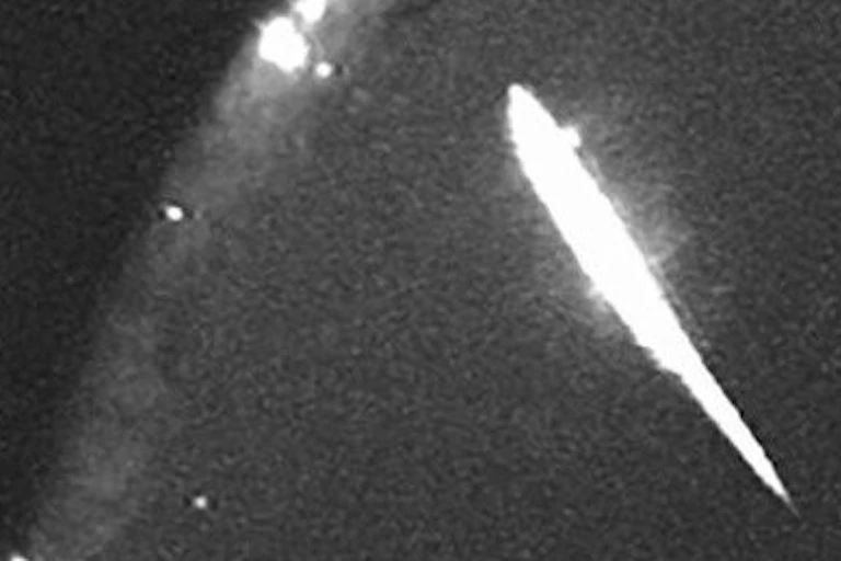 A black and white image of a bright white fireball in the Earth's atmosphere.