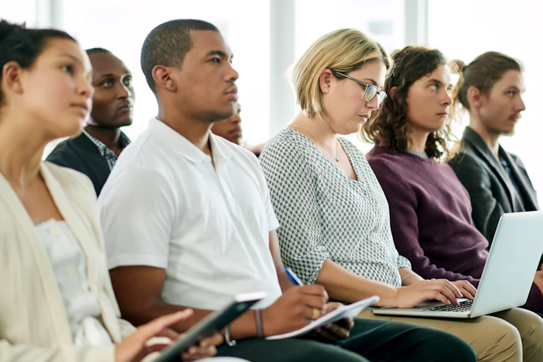 Multicultural employees sit in a row at a meeting.