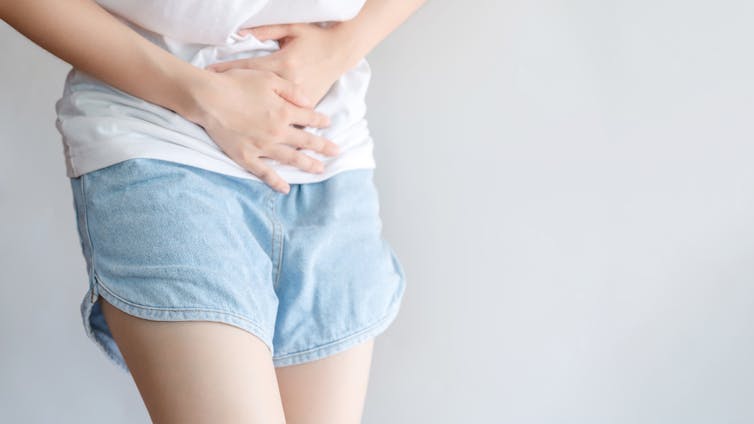 Person pressing hands against stomach