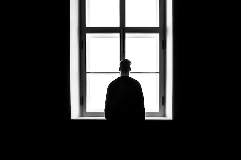 A man photographed from behind looking out a window.