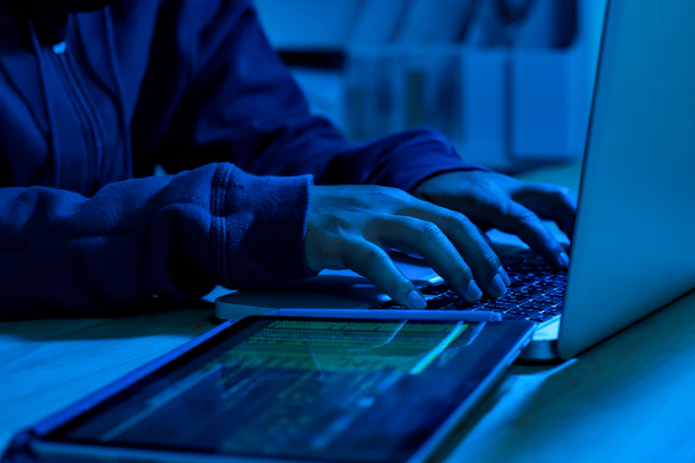 Person typing on a laptop in blu light