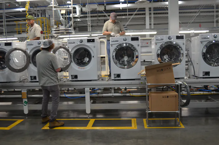 Employees work on an assembly line of washing machines