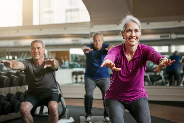 Three adults with gray hair exercising in a gym