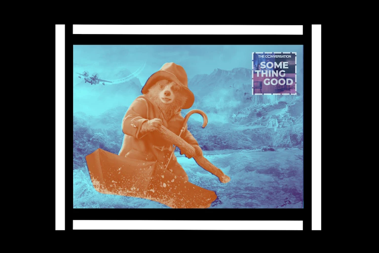 Paddington riding in the ocean in an umbrella