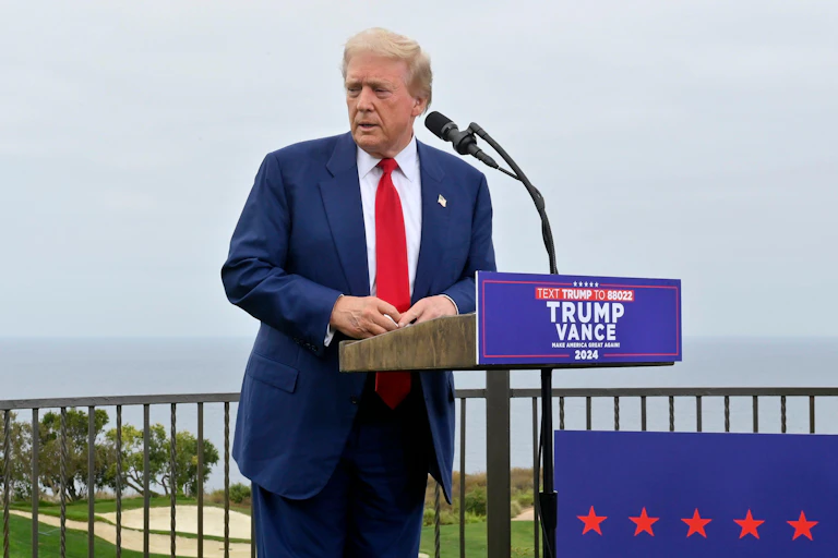 Donald Trump stands in front of a microphone.