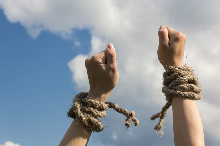 Hands breaking the rope tied around wrists