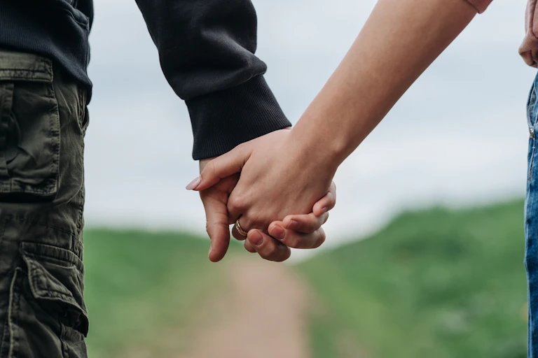 Close up of a couple holding hands walking around a path