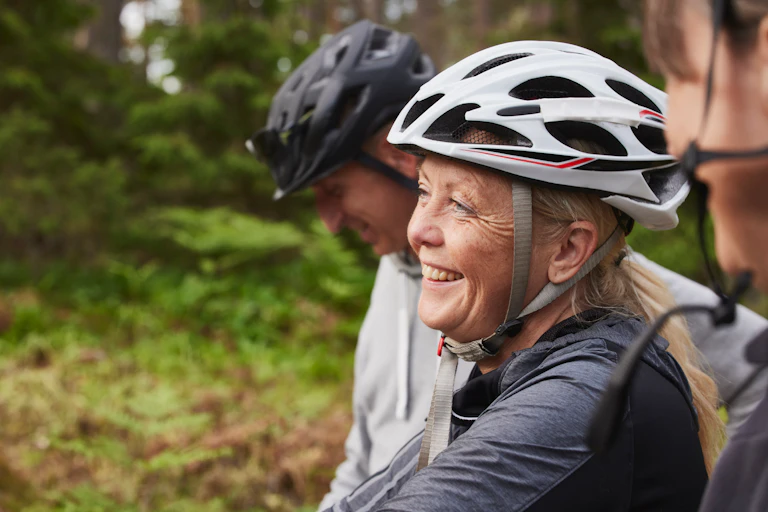 A group of people sitting on a bench wearing bike helmets.