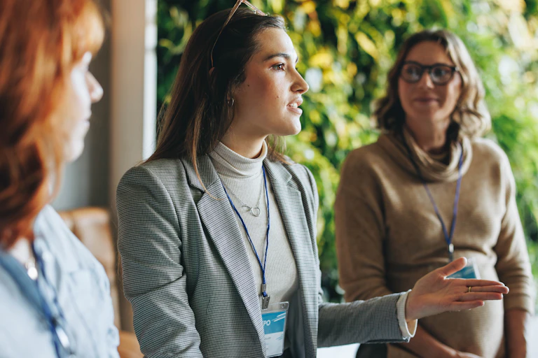 Three women wearing lanyards having a conversation
