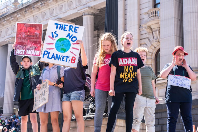 Children shout and hold signs at school strike for climate.