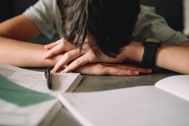 As young person puts their head on a deck.