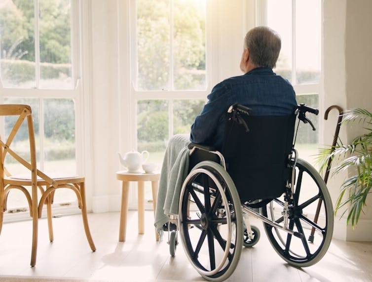 Man in wheelchair looking out of a window