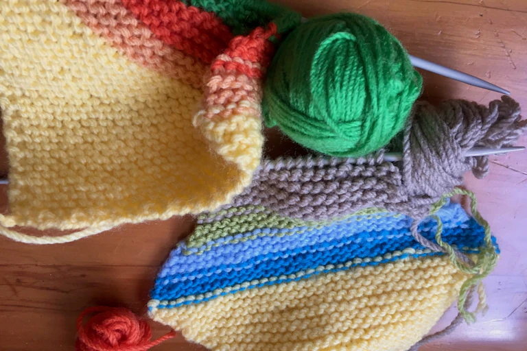 Colourful knitting with needles and balls of wool on a table.