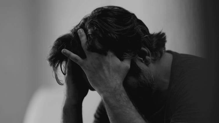 Black and white photo of a man with his head in his hands.