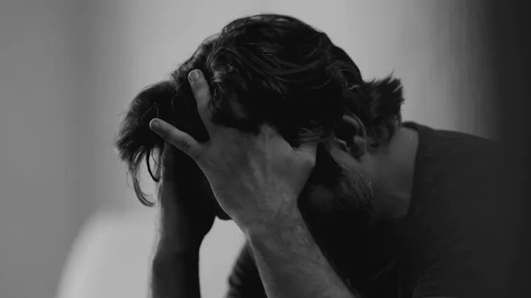 Black and white photo of a man with his head in his hands.