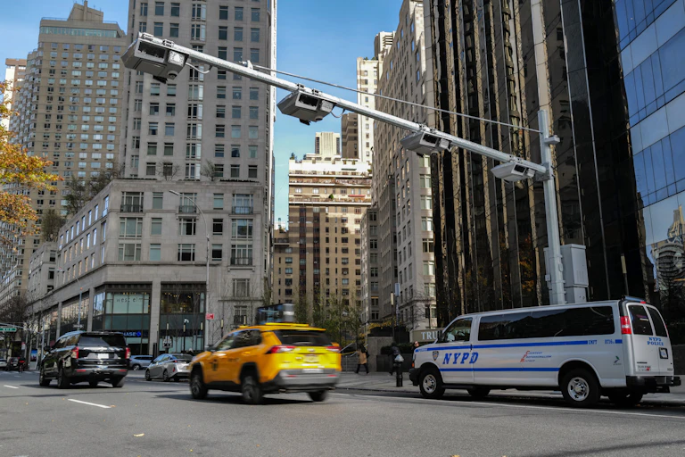 Cars drive under four cameras mounted on a large metal arm over the street