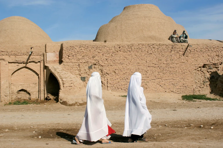 Two women walking past a madrasa.