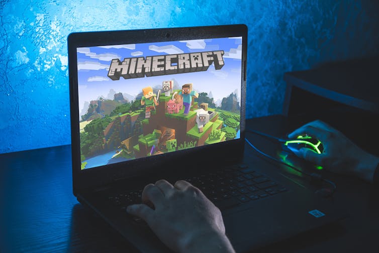 A person playing Minecraft on a laptop.