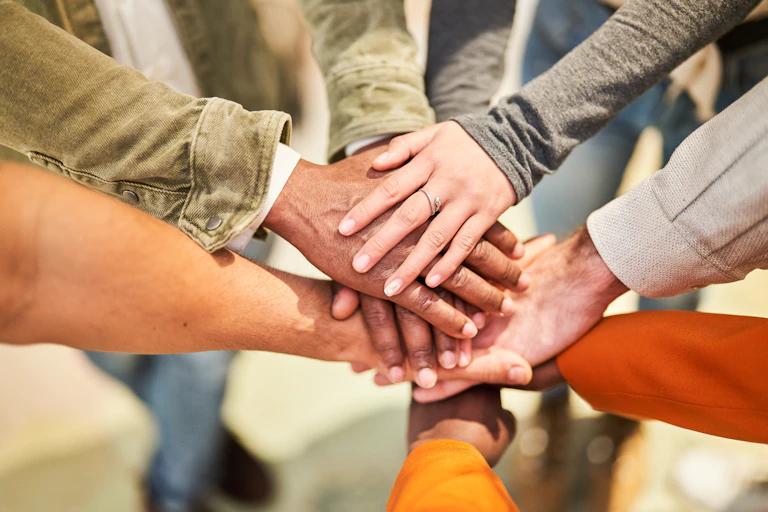 Various people put their hands together in a circle.