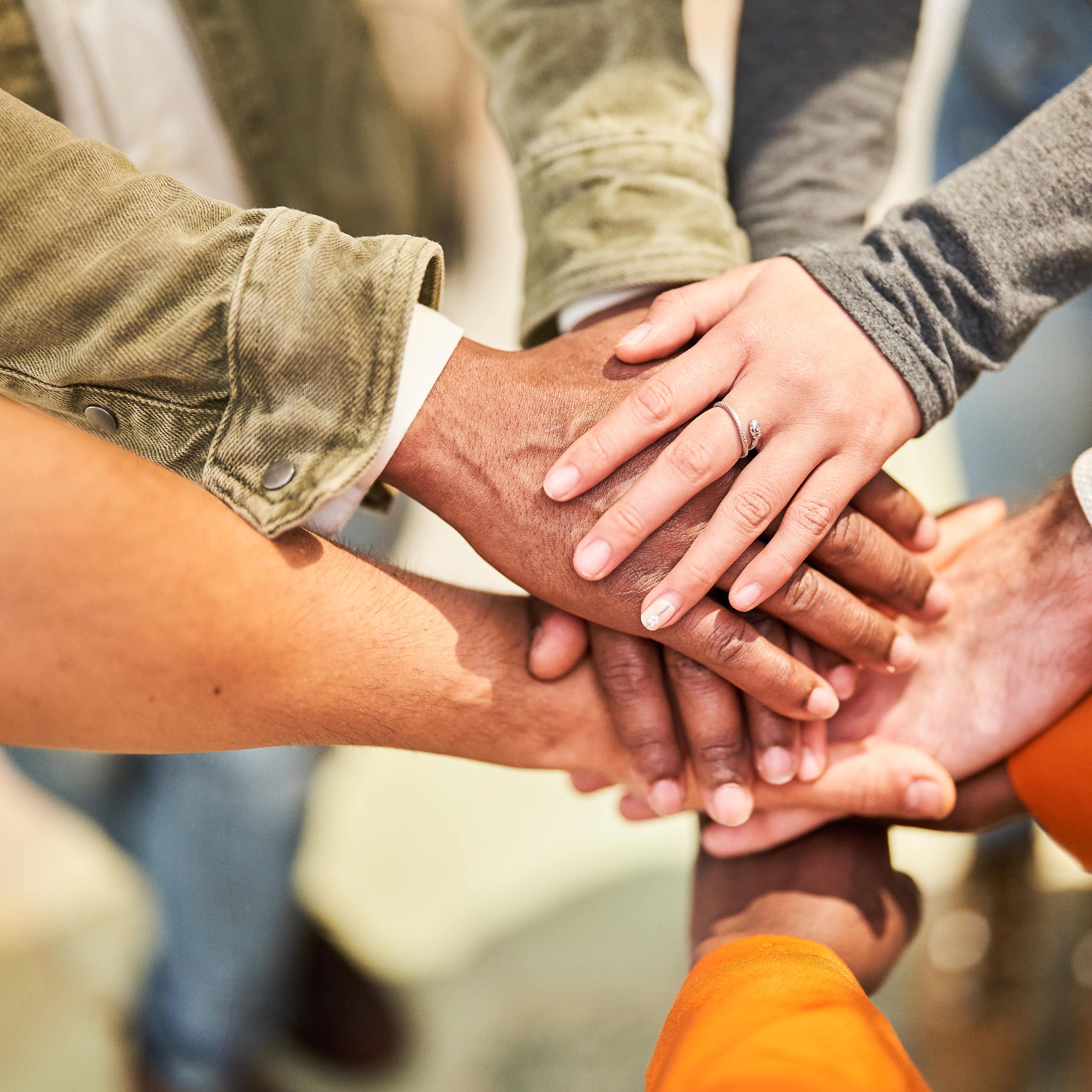 Various people put their hands together in a circle.