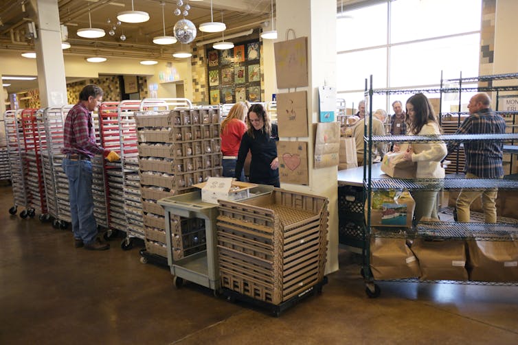 People stand at tables moving small boxes into different piles.