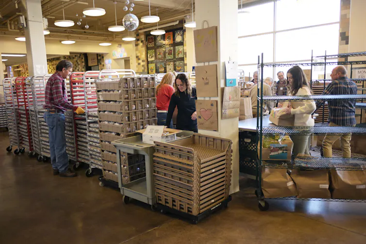 People stand at tables moving small boxes into different piles.