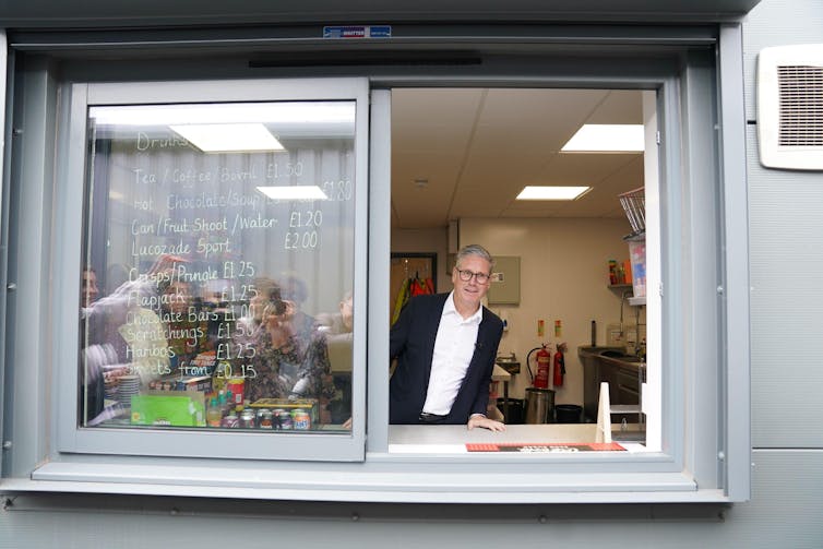 Keir Starmer olhando pela janela de uma cabine portátil.
