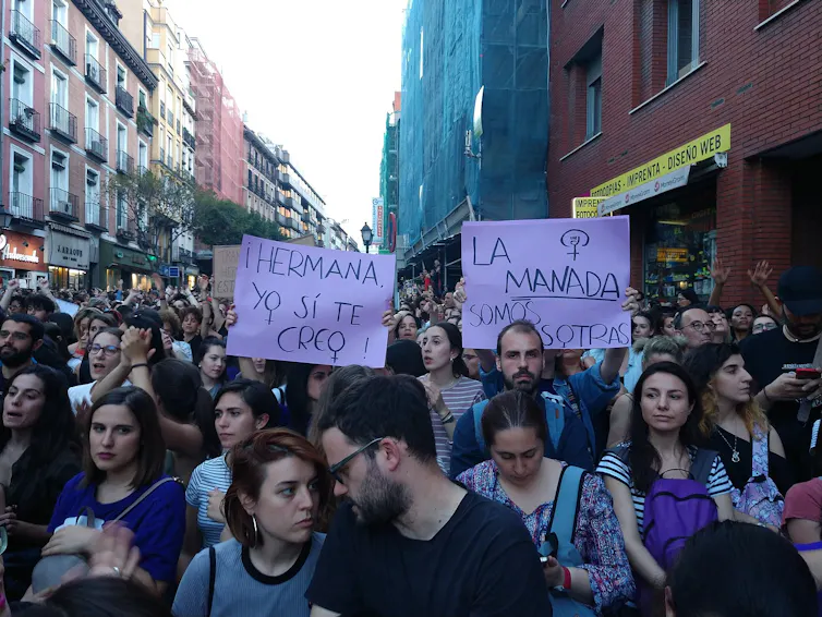 Des manifestants dans une rue de Madrid, tenant des affiches violettes