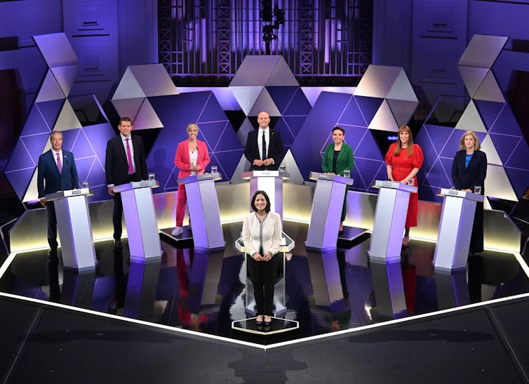 Sete representantes partidários em pódios em um estúdio de TV.
