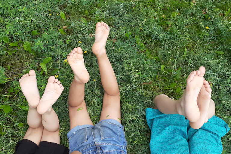 Bare legs of three children lying on grass.