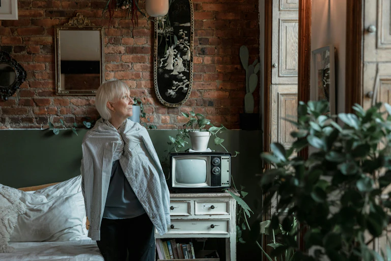 An older woman looks out the window.