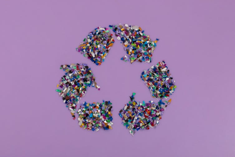 purple background, recycling symbol made of coloured plastic fragments