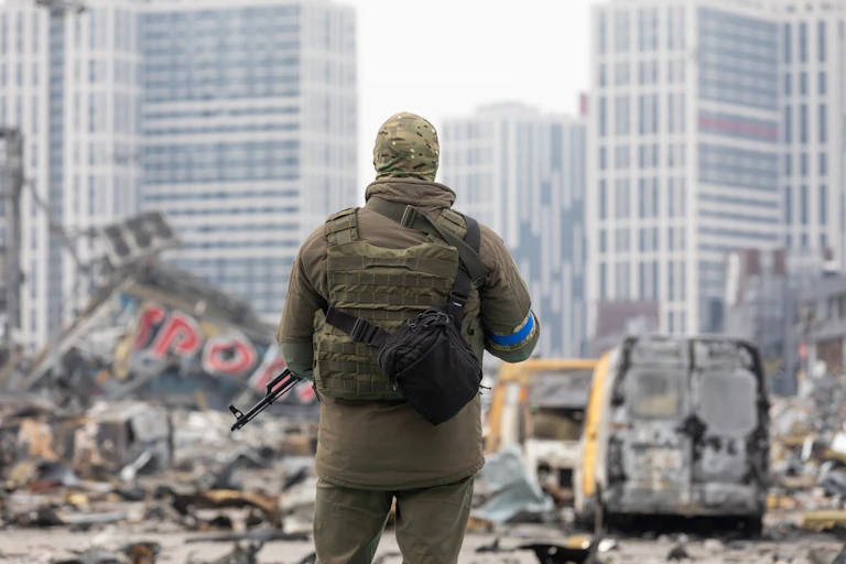 A Ukrainian soldier looking at a war-damaged city.
