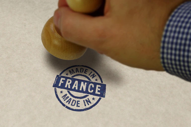 Une main tamponne « Made in France » sur un emballage.
