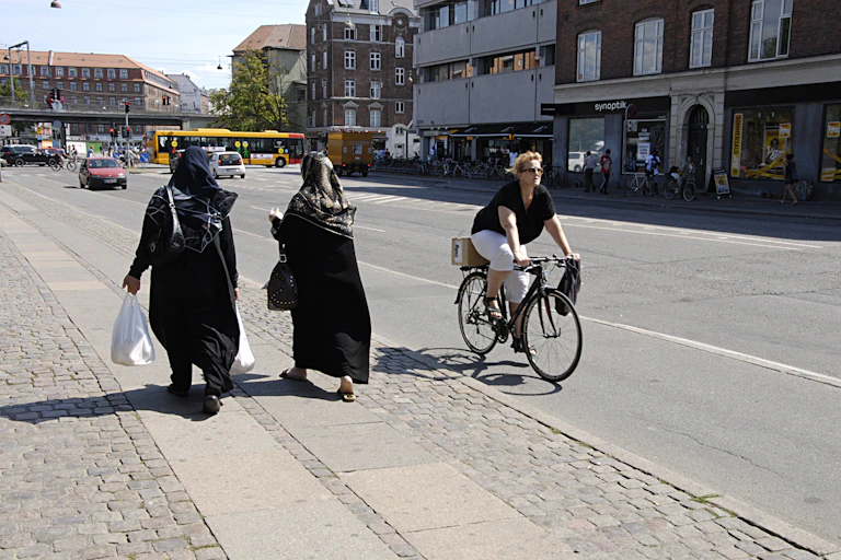 Biker passes people walking.
