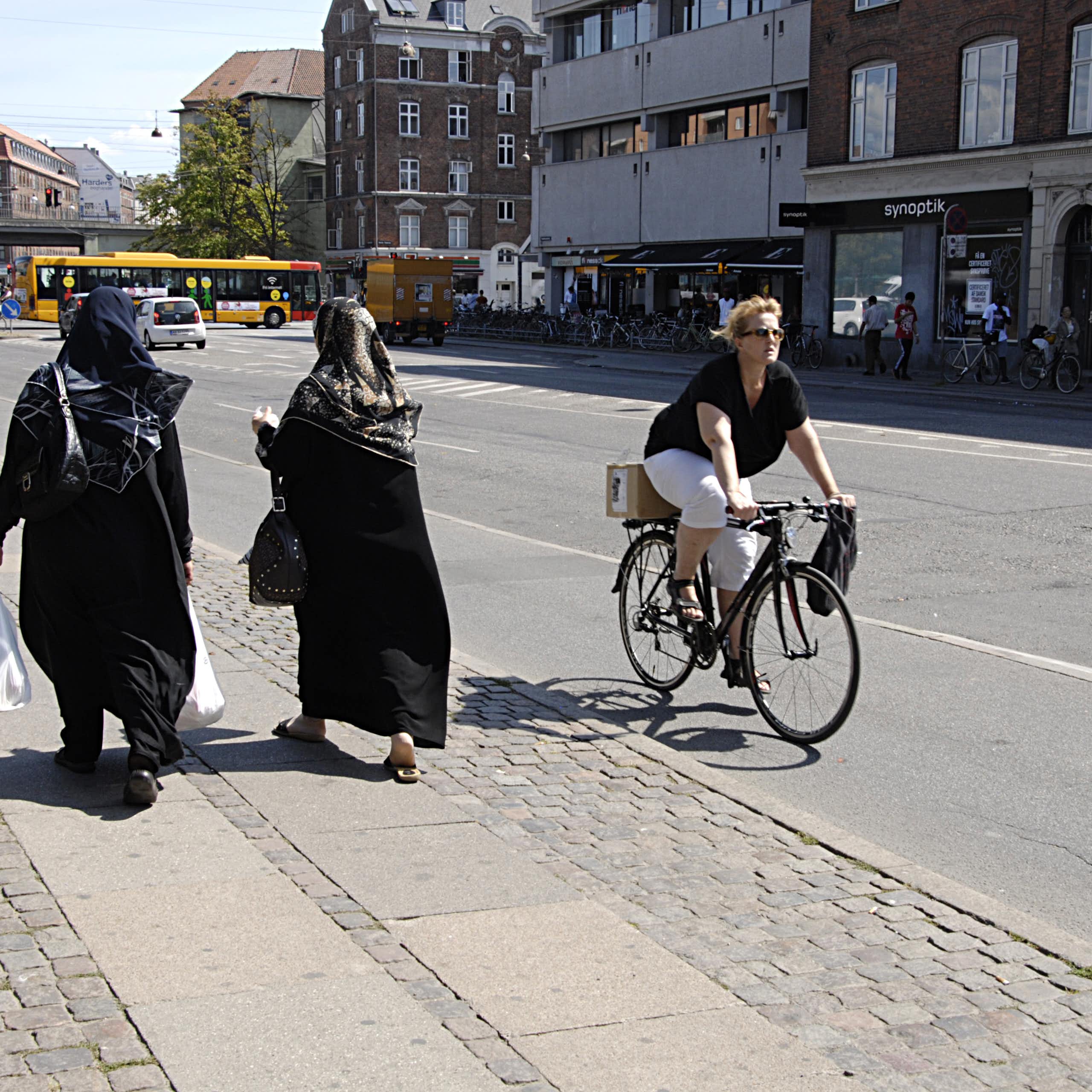 Biker passes people walking.
