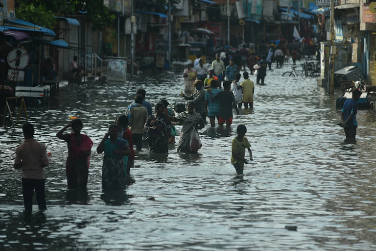A procession of people wading through a flooded street.