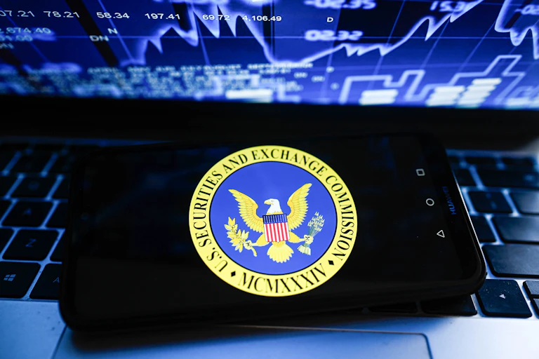 Phone on laptop with a stock market-related chart on the computer screen..