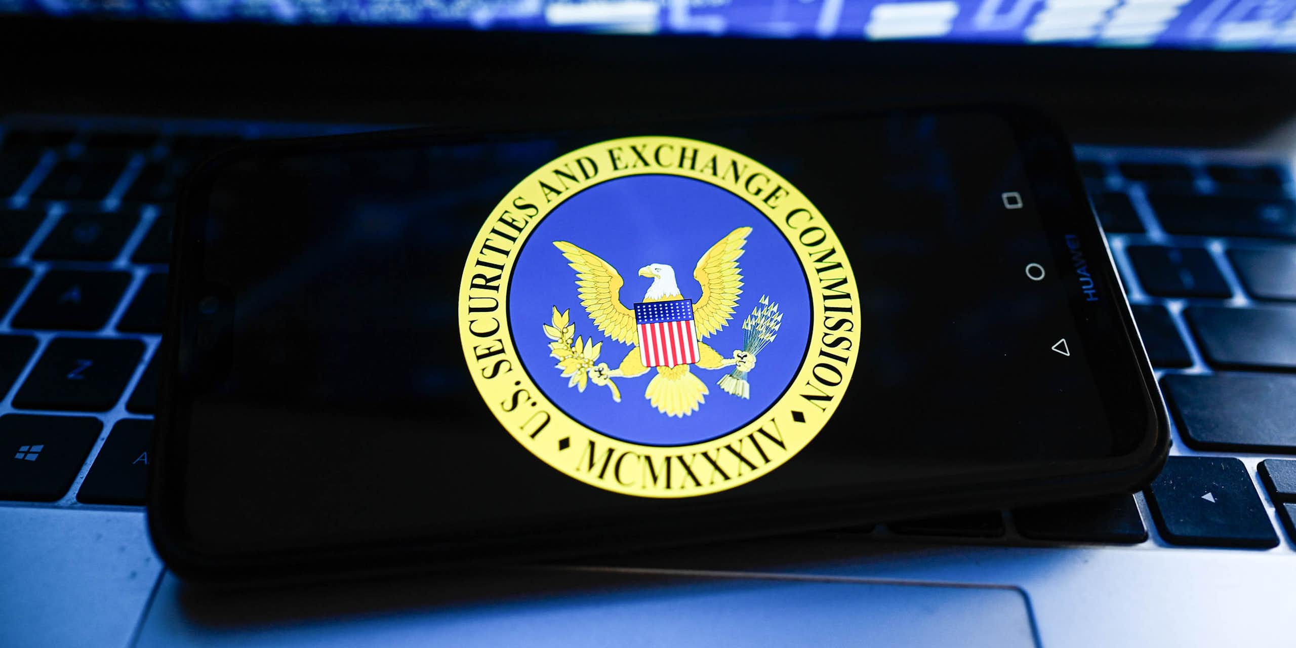 Phone on laptop with a stock market-related chart on the computer screen..