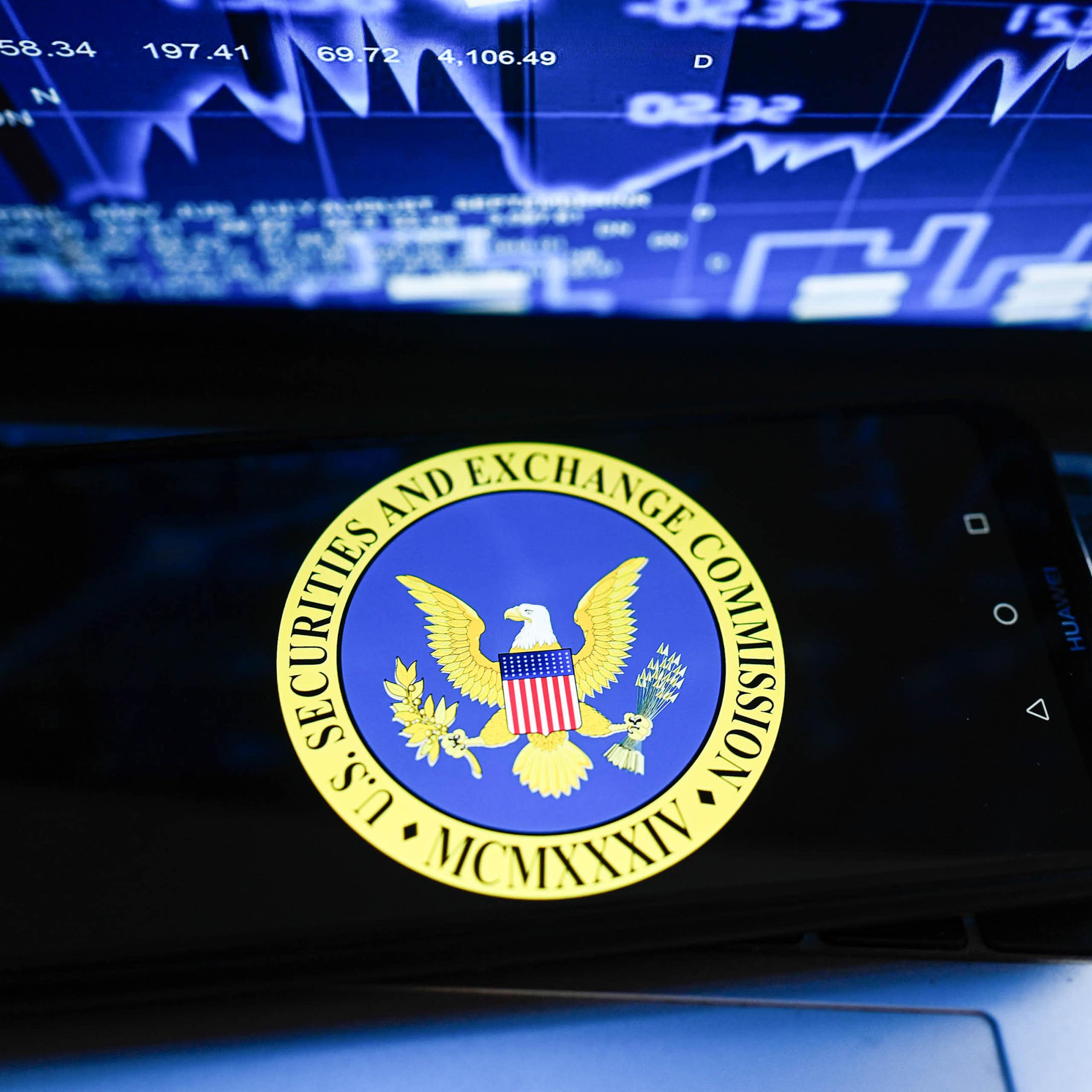 Phone on laptop with a stock market-related chart on the computer screen..